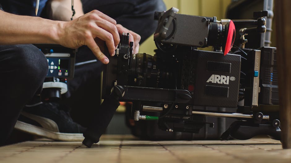 Close-up of hands adjusting a professional ARRI film camera on a production set, showcasing filmmaking equipment.