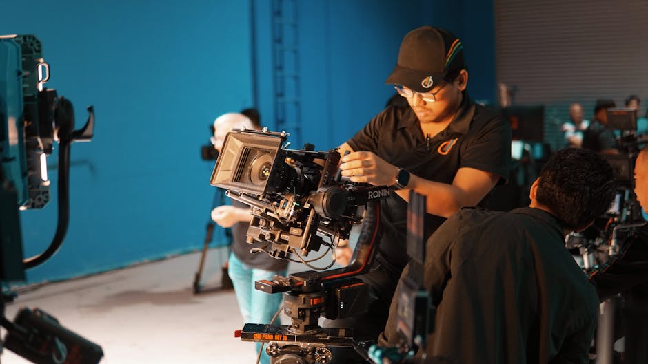 Film crew setting up professional camera equipment in a studio for shooting.