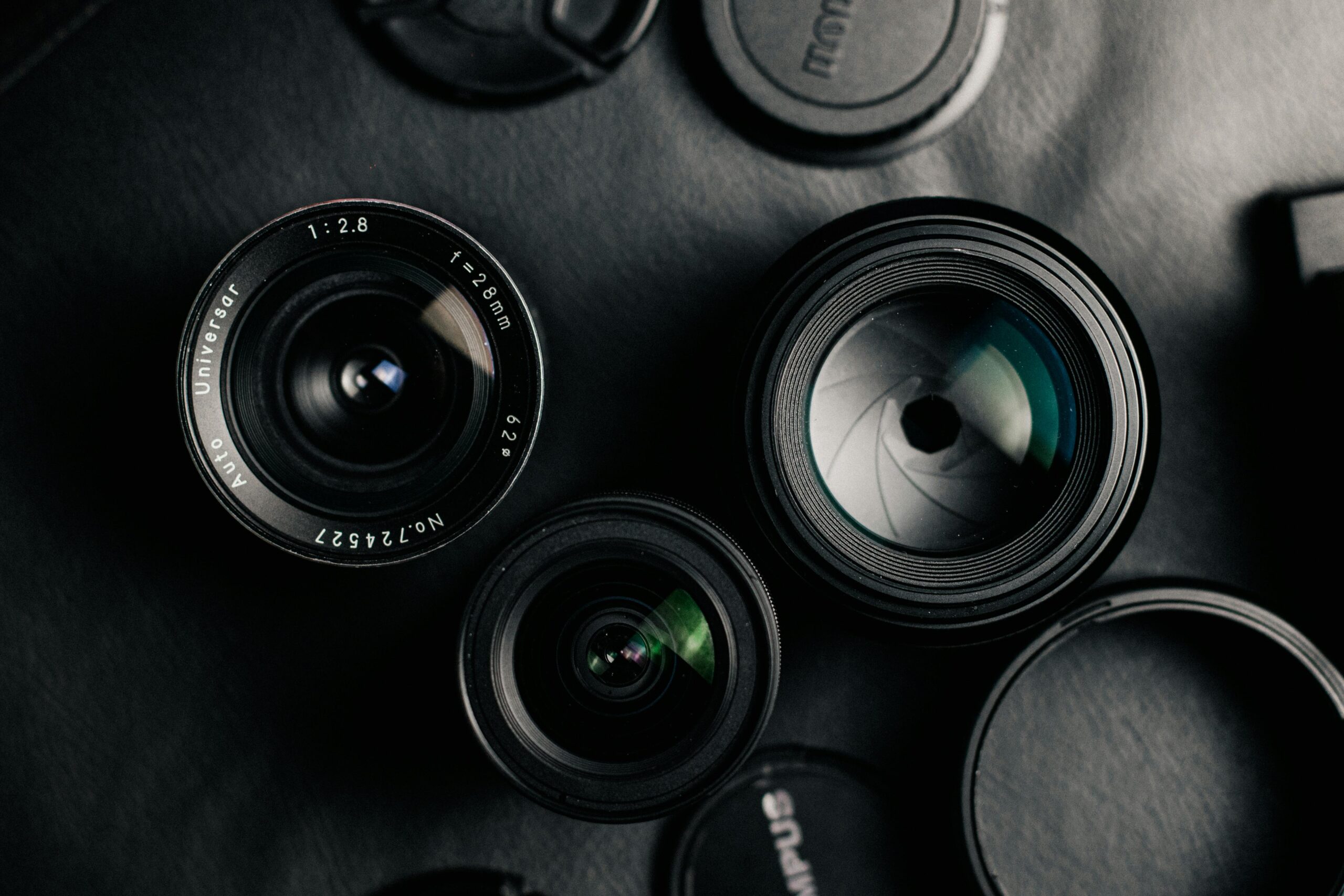 Detailed view of camera lenses arranged on a dark background, showcasing photographic equipment.
